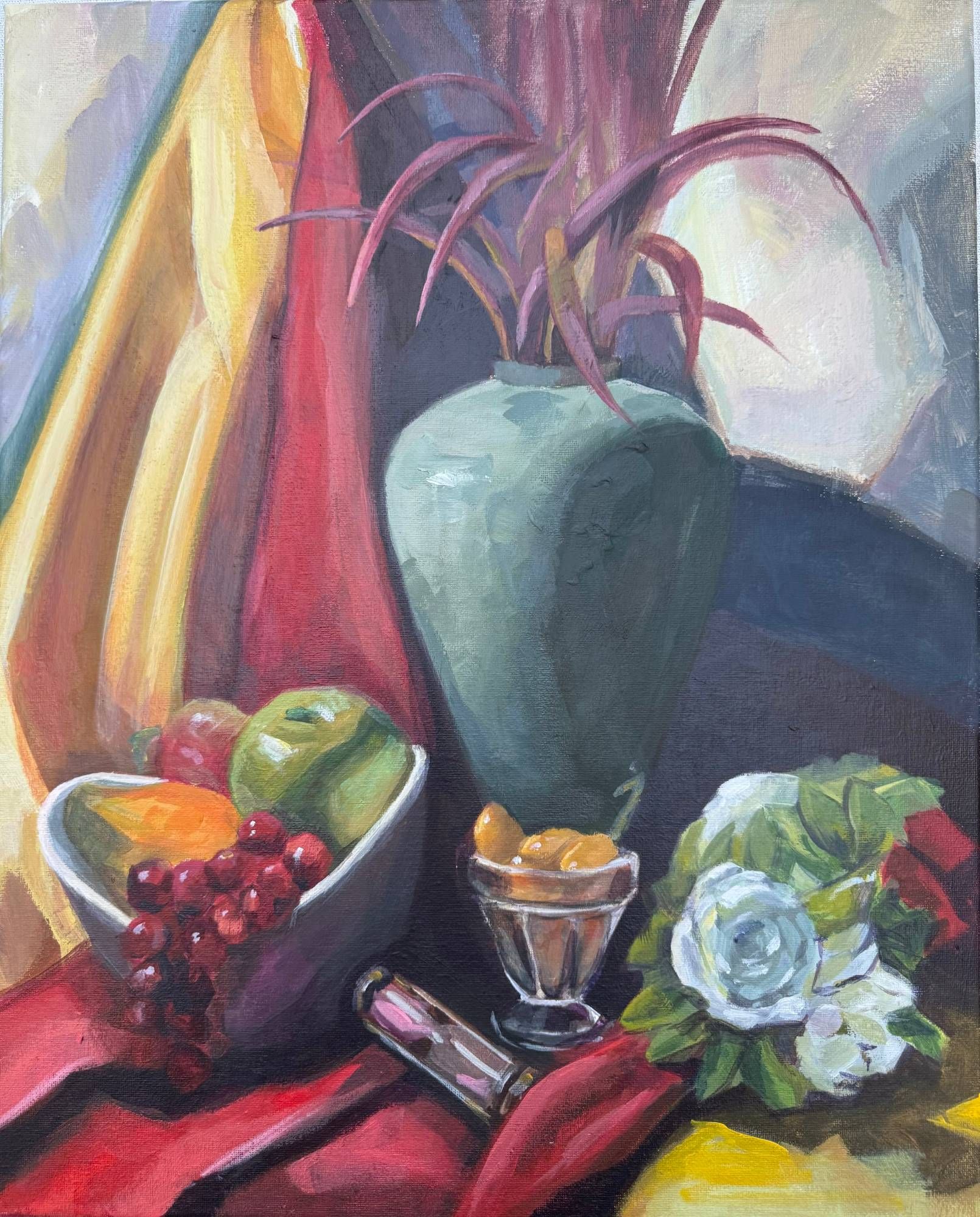 Vertical still life painting of a pale green-grey vase holding spiky magenta leaves, set against draped yellow and red fabric, with a white bowl of apples, an orange and red grapes, a footed glass of apricots, a small hourglass and white roses on a red cloth.